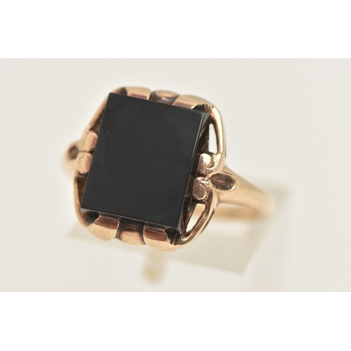 404 - A YELLOW METAL GEM SET RING, a rectangular cut onyx, prong set in yellow metal with slightly tapered... 
