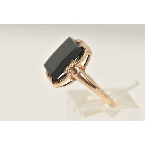 404 - A YELLOW METAL GEM SET RING, a rectangular cut onyx, prong set in yellow metal with slightly tapered... 