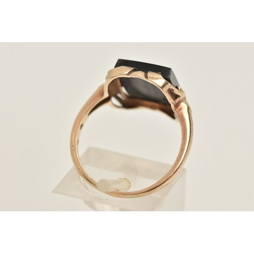 404 - A YELLOW METAL GEM SET RING, a rectangular cut onyx, prong set in yellow metal with slightly tapered... 