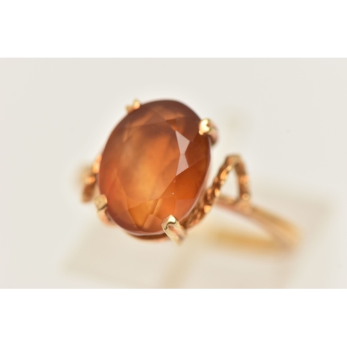 411 - A YELLOW METAL GEM SET RING, an oval cut deep orange brown Citrine, prong set in yellow metal, stamp... 