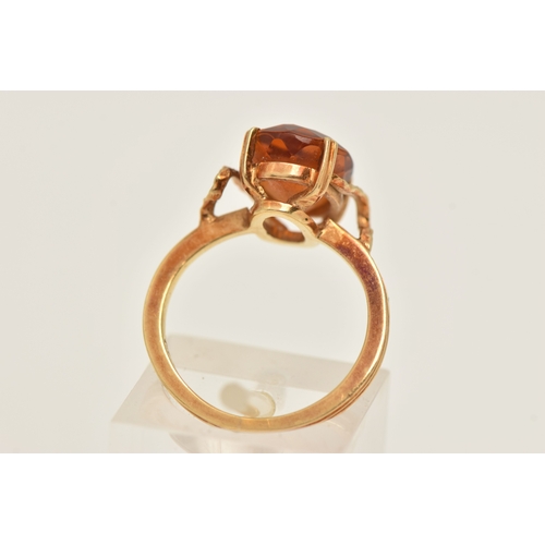 411 - A YELLOW METAL GEM SET RING, an oval cut deep orange brown Citrine, prong set in yellow metal, stamp... 