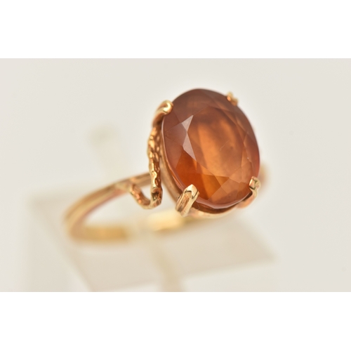 411 - A YELLOW METAL GEM SET RING, an oval cut deep orange brown Citrine, prong set in yellow metal, stamp... 