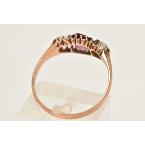 417 - A ROSE METAL GEM SET RING, AF set with a central oval cut garnet claw set and flanked with two circu... 