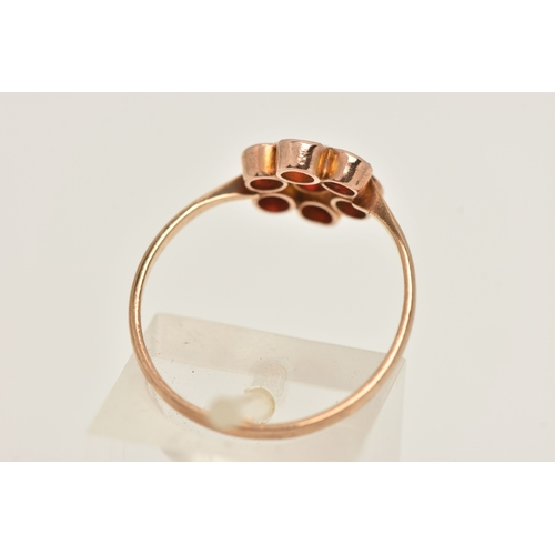 418 - A YELLOW METAL GARNET SET FLOWER RING, set with seven circular cut garnets, milgrain settings, to th... 