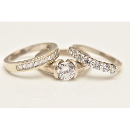 THREE WHITE METAL RINGS, to include a seven stone cubic zirconia ring ...
