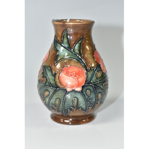821 - A MOORCROFT POTTERY BALUSTER VASE, tube-lined with red flowers and forest green leaves on a brown gr... 