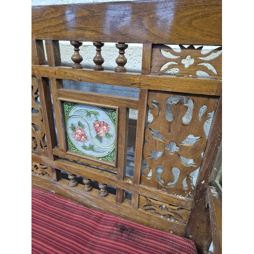 306 - AN ANGLO INDIAN TEAK BENCH, with a railway-style swinging back rest, inlaid with various tiles, rais... 