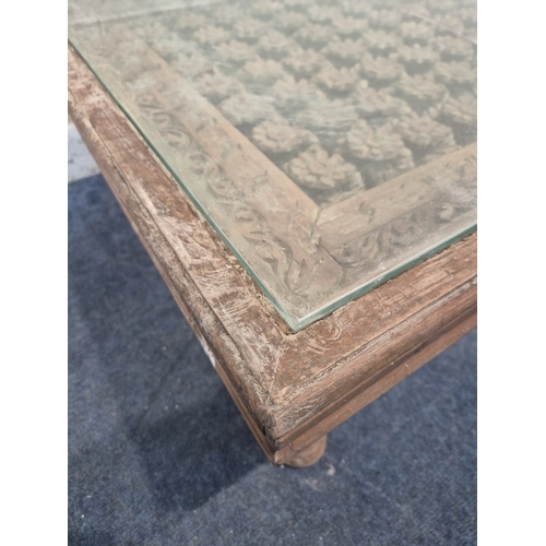 312 - A CARVED INDIAN RECTANGULAR COFFEE TABLE, with a glass insert, raised on block and turned legs, widt... 