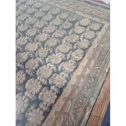 312 - A CARVED INDIAN RECTANGULAR COFFEE TABLE, with a glass insert, raised on block and turned legs, widt... 