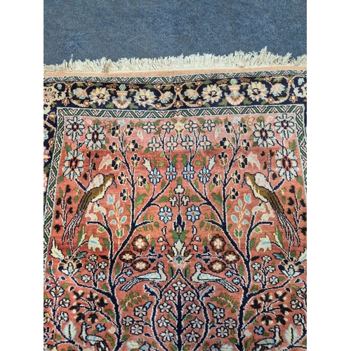 A RED GROUND WOOLEN RECTANGULAR RUG, depicting birds in a tree, flowers ...