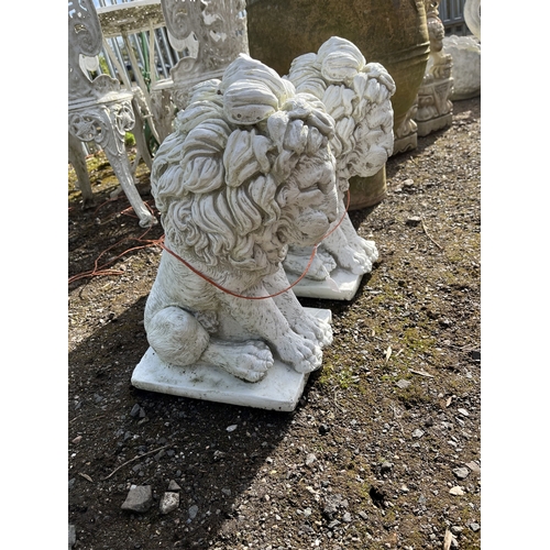 32 - A PAIR OF CONCRETE LION FIGURES seated on a pad, 44cm high. Condition Report: no obvious damage