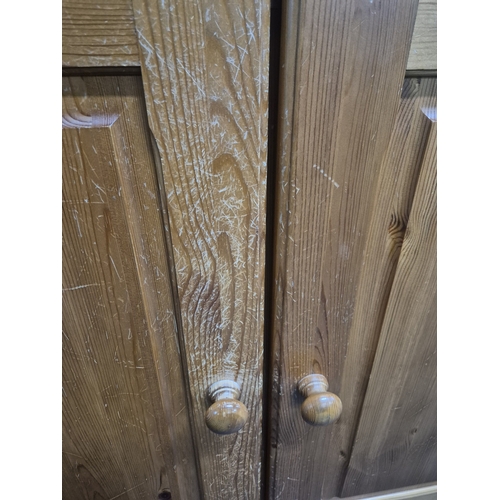 206 - A MODERN PINE LOW WARDROBE, with three cupboard doors and two drawers, raised on bun feet, width 142... 