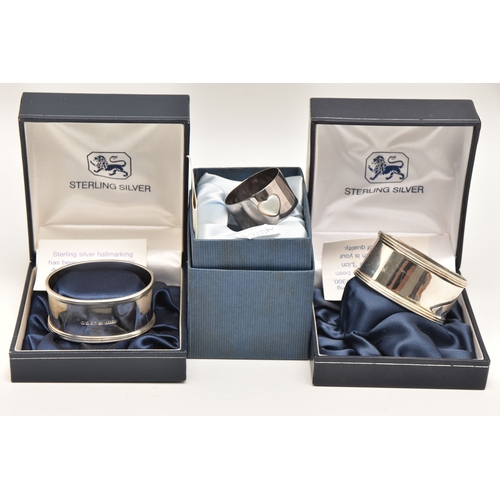 592 - THREE BOXED SILVER NAPKIN RINGS, two oval form and a small circular napkin rings, each with a full s... 