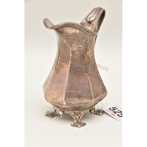 525 - AN EARLY 20TH CENTURY SILVER MILK JUG, faceted form with scroll handle, raised on four feet, hallmar... 