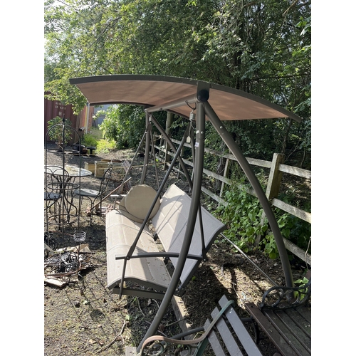 21 - A METAL FRAMED SWINGING GARDEN BENCH, with fabric shade and seats 190cm wide, Condition Report: shad... 