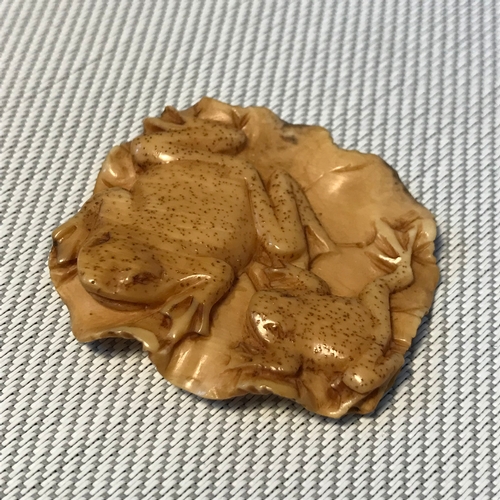 273 - A Japanese Meiji period carved netsuke detailing a lily pad with two frogs. Signed. Measures 4cm in ... 