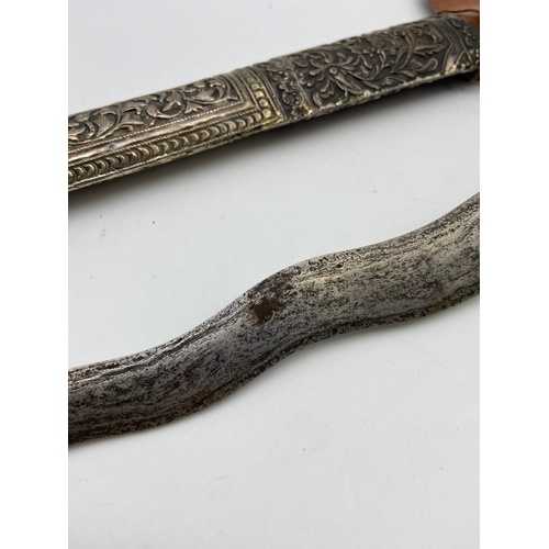 5A - A 19th century Kris or Keris dagger with silver ornate sheath. Handle is made of wood and silver mou... 