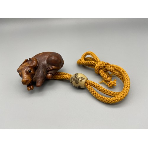 160J - A Meiji period hand carved Japanese netsuke of an Ox laying down, Design with black bead eyes, signe... 