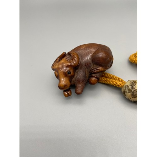 160J - A Meiji period hand carved Japanese netsuke of an Ox laying down, Design with black bead eyes, signe... 