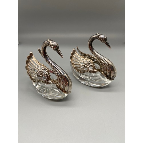 26 - A Pair of Import London silver swan salt dishes. Designed with articulated wings and crystal cut bod... 