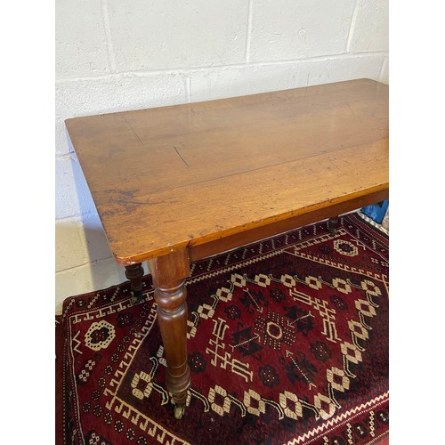 82A - A 19th century mahogany farmhouse dining table. Designed on turned leg supports and brass castor fee... 