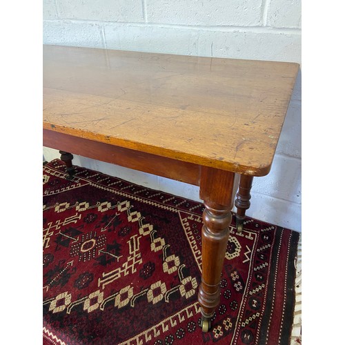 82A - A 19th century mahogany farmhouse dining table. Designed on turned leg supports and brass castor fee... 