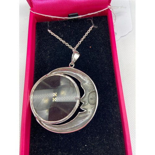 177J - A Silver magnifying pendant with necklace. The pendant is in the form of a half moon.