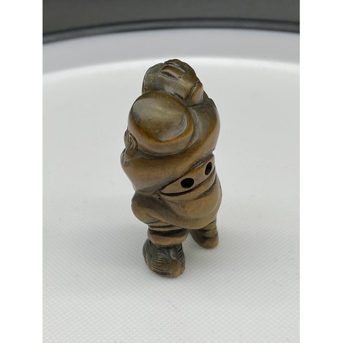 140J - A Japanese hand carved netsuke of a gentleman carrying a bag. Signed.