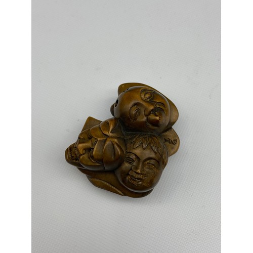 109J - A Japanese hand carved netsuke of 7 Oni masks clustered together. Signed. [4.5cm at widest point]