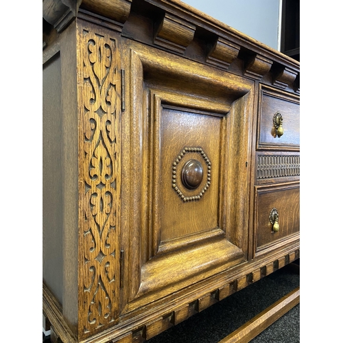 66 - An antique solid oak Art Deco sideboard designed on bulbous carved leg supports and decorative carve... 