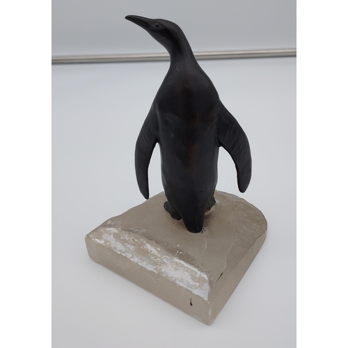 219 - A Cold painted penguin figurine sat upon an iceberg. [12cm in height]