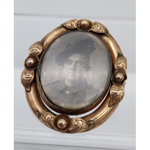 521 - A Yellow metal ornate mourning brooch showing military gentleman, photograph.