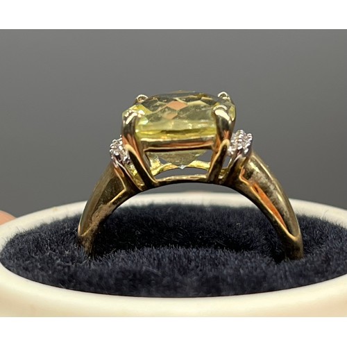 40 - A Ladies 9ct yellow gold ring set with a large pale yellow stone off set by diamonds to each shoulde... 