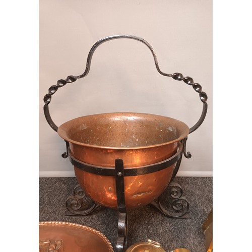 800 - Copper pot in a metal swing handle surround with fire brasses, together with a copper plaque, the cr... 