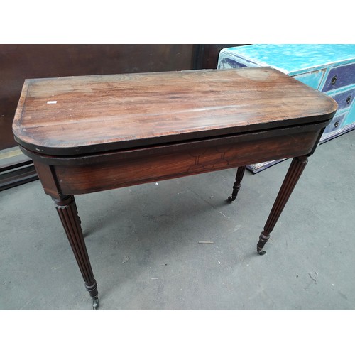 254 - Antique mahogany folding games table, supported on turned legs and castor feet.