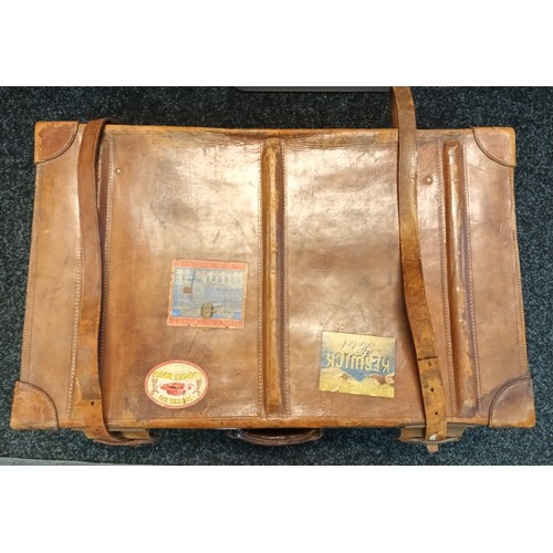 858 - Antique tan leather travel case. Fitted with straps and has original travel stickers showing.