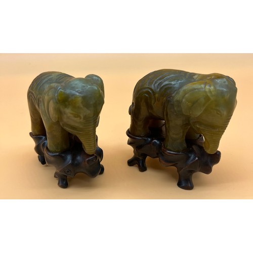 561 - Two Chinese hand carved elephant sculptures sat upon wooden carved stands. [8cm high]