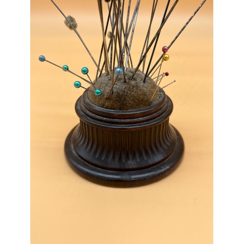 565 - 19th century turned wood pin cushion containing various sized hat pins.