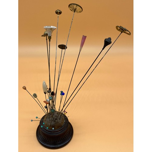 565 - 19th century turned wood pin cushion containing various sized hat pins.