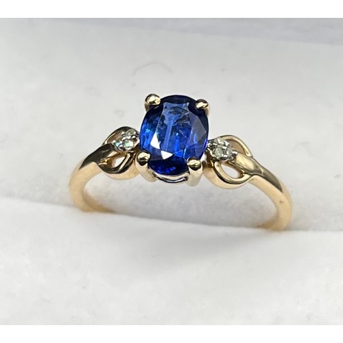 38 - 10ct yellow gold ring set with a single blue spinel stone off set by diamonds. [Three diamonds to ea... 