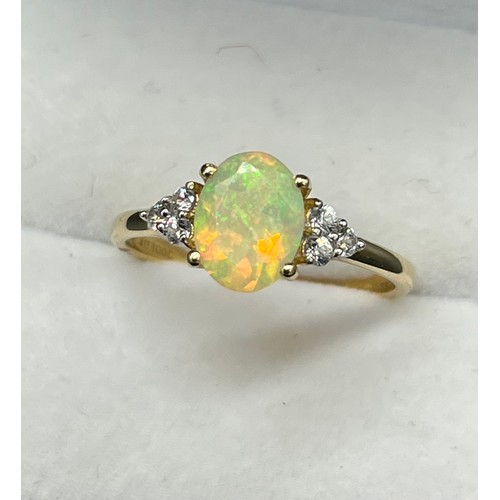 46 - 10ct yellow gold ladies ring set with an Oval cut opalescent style centre stone off set by three whi... 