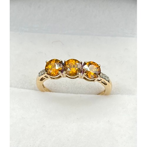 54 - 10ct yellow gold ladies ring set with three round cut orange tanzanite stones off set with diamond s... 