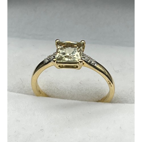 58 - 10ct yellow gold ladies ring set with a princess cut pale green topaz off set by diamond stone shoul... 