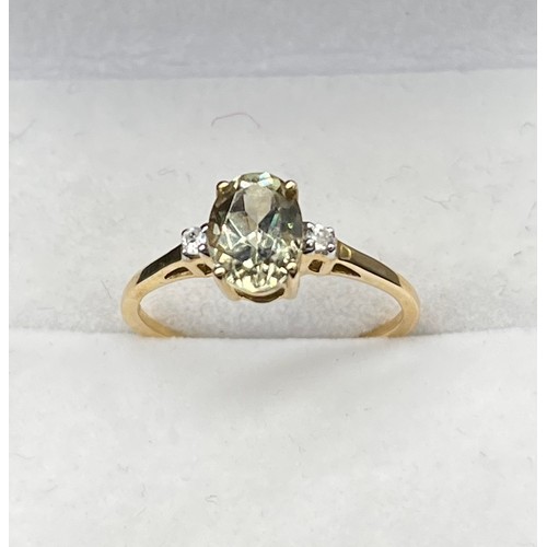 60 - 10ct yellow gold ladies ring set with a single oval cut pale green spinel stone off set by white spi... 