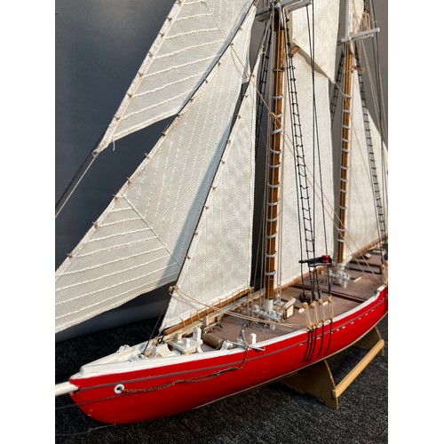 136 - A Large hand built sailing ship fitted with sails and rigging. Comes with wooden stand. [69x79cm]