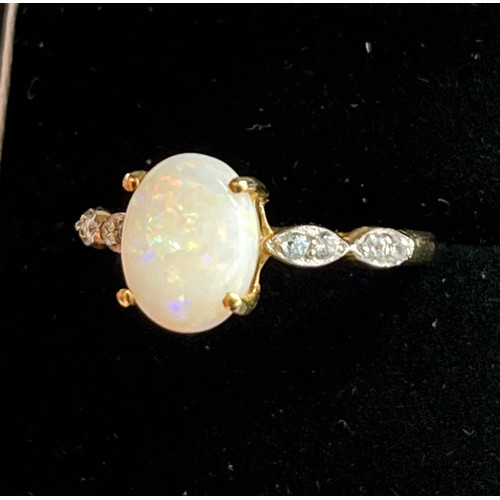 46 - 10ct yellow gold ladies ring set with a single oval cut opal off set by white topaz shoulders. [Ring... 