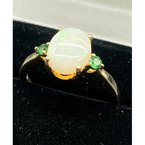 59 - 10ct yellow gold ladies ring set with an oval cut opal centre stone off set by green Tourmaline ston... 