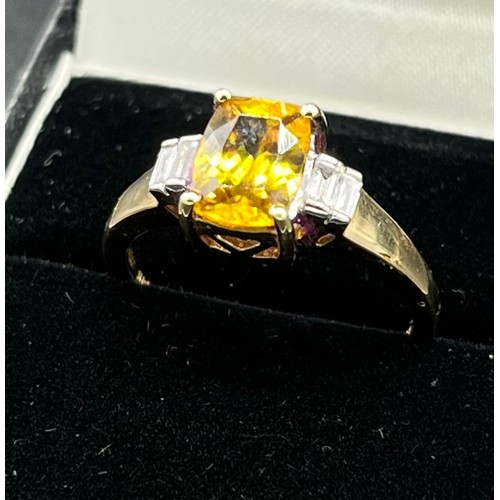 69 - 14ct yellow gold ladies ring set with a large yellow tourmaline stone off set by emerald cut diamond... 