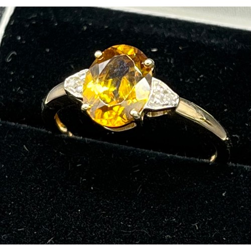 70 - 10ct yellow gold ladies ring set with a large oval cut orange/ yellow tourmaline stone off set by di... 