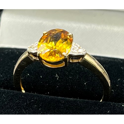 70 - 10ct yellow gold ladies ring set with a large oval cut orange/ yellow tourmaline stone off set by di... 